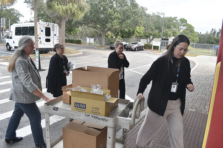 Jennifer Brock helps to drop off a donation of Magiscopes at the Lee Wetherington Club location of Boys & Girls Clubs of Sarasota and DeSoto Counties, as Roscelyn Guenther, senior director of program services at Boys & Girls Clubs, along with Jillian Diblasi and Rachel Howard, enrichment director and academic success director at the Lee Wetherington Club, pull the boxes inside.