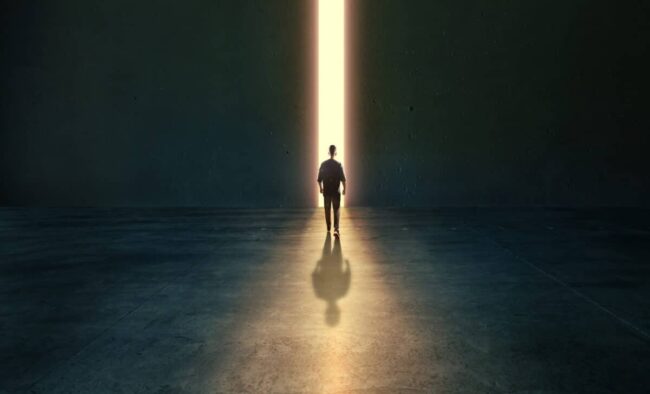a-man-walks-towards-the-light-in-a-dark-empty-space-1200×727.jpg