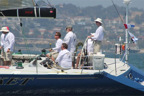 Photo of a group of people manning a sailboat.