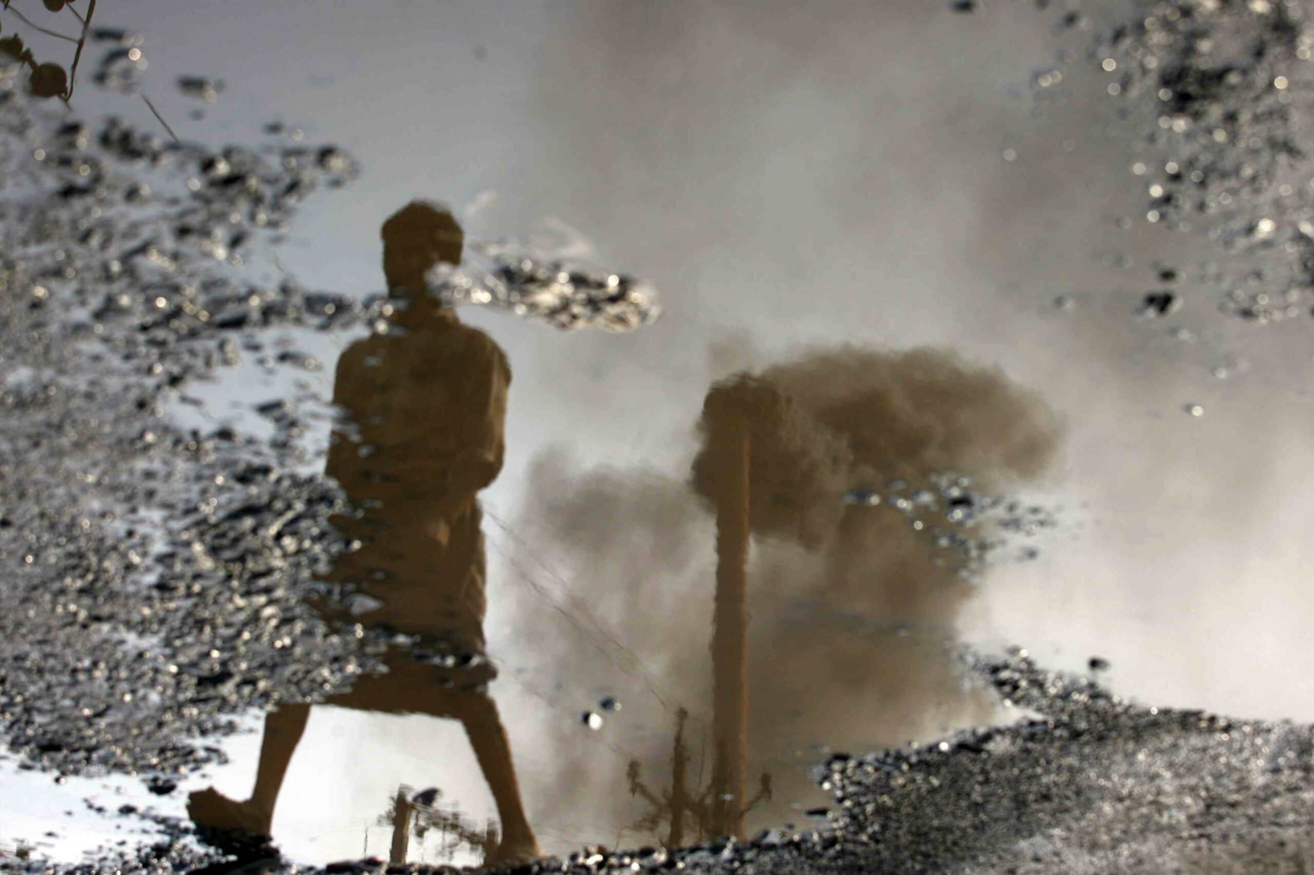 A chimney is reflected in a puddle polluted with chemicals in Surat in November 2009. Credit: Reuters.