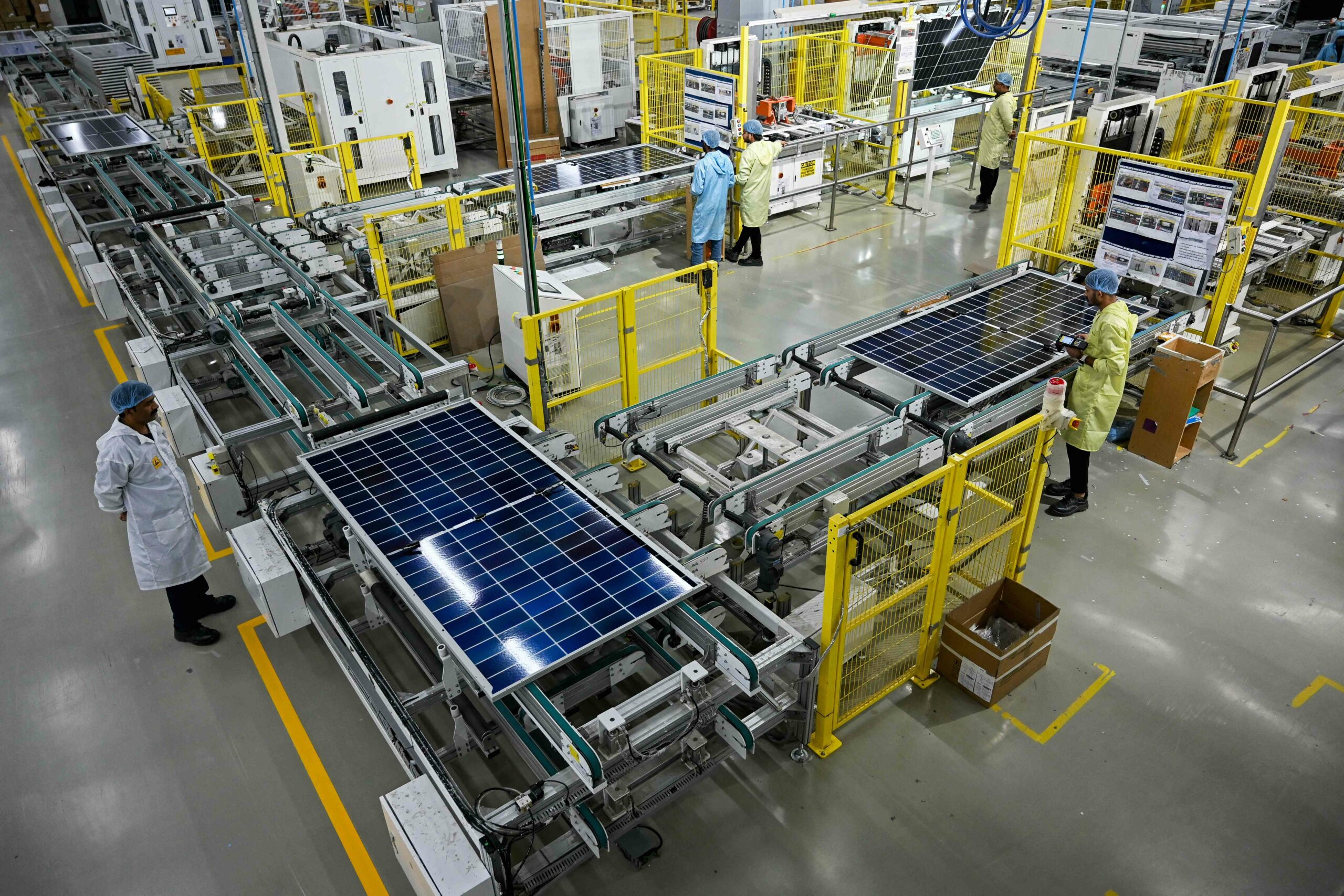 Employees inspecting solar panels on assembly lines at an Adani Group factory in Mundra, Gujarat, in November 2025. Credit: AFP.