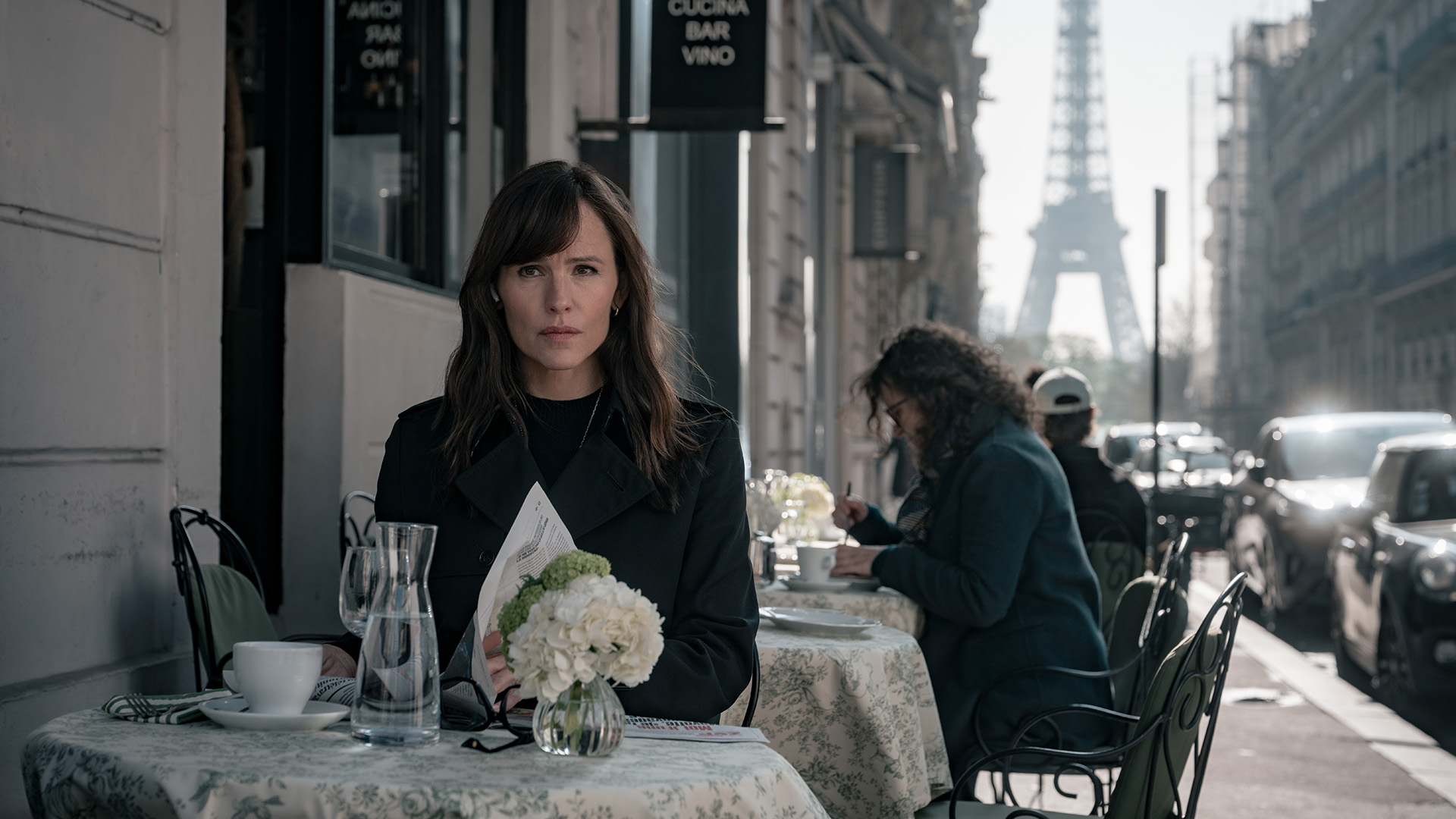 Jennifer Garner as Hannah Hall, sitting in Paris with the Eiffel Towel in the background, in The Last Thing He Told Me season 2.