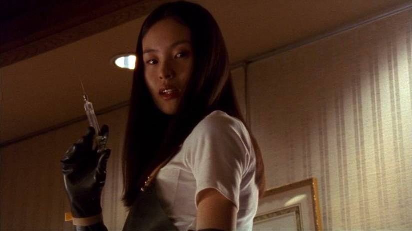 A woman in a white shirt with black gloves prepares a deadly syringe in Takashi Miike’s Audition