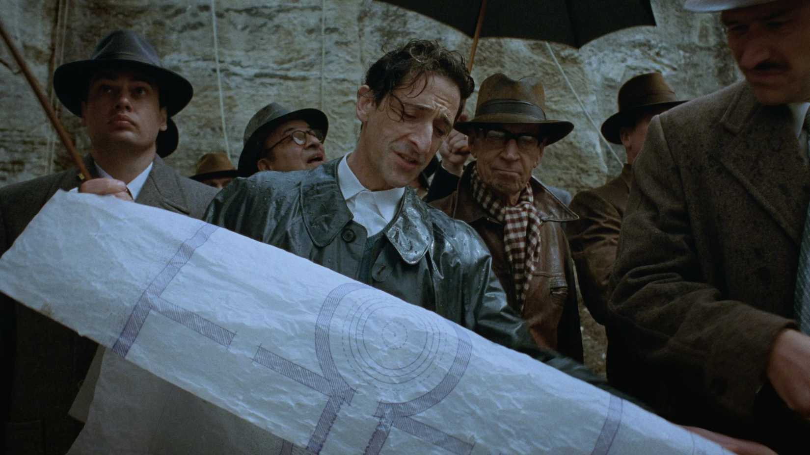 Adrien Brody as László Tóth looking at building plans in The Brutalist