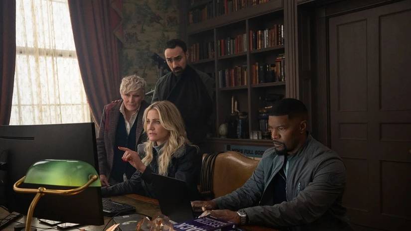 Four stars of Back in Action huddled around a computer as Cameron Diaz points at the screen