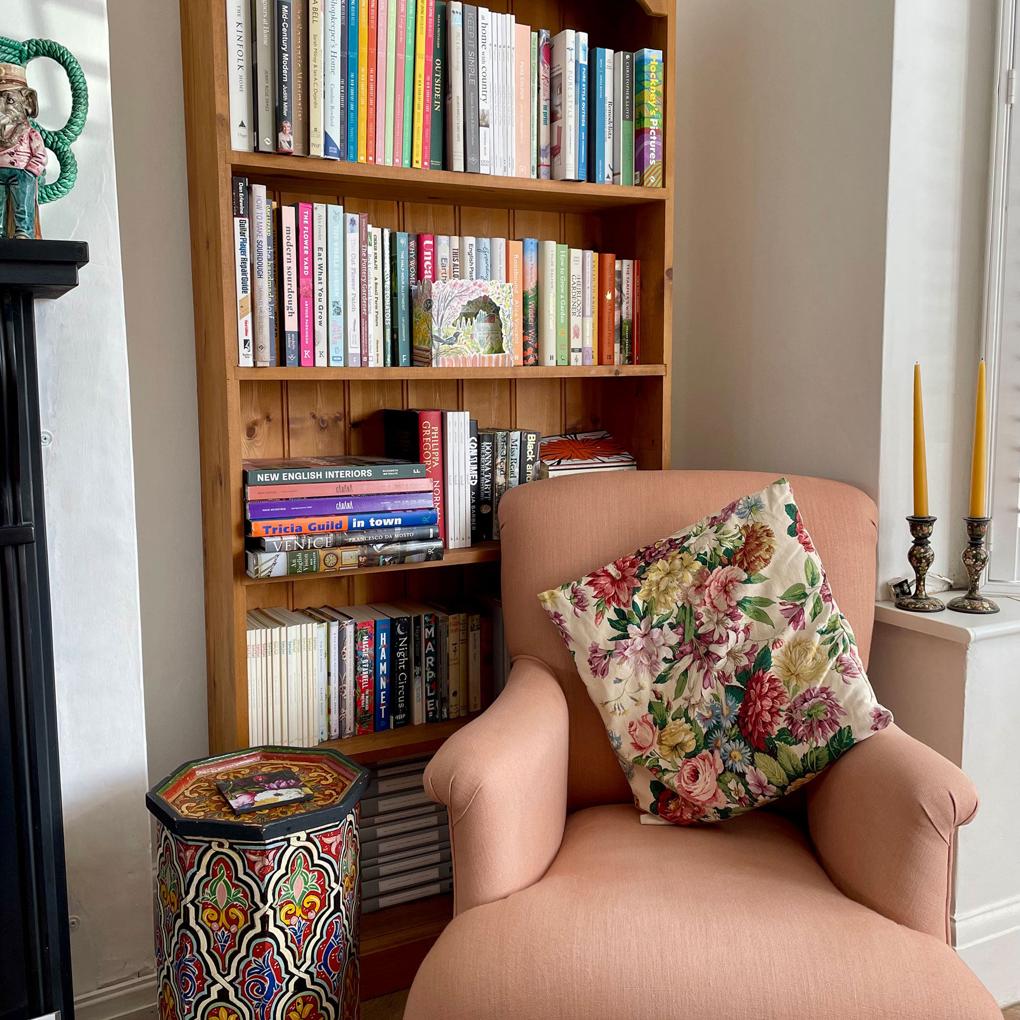 Corner of room with armchair beside wooden bookcase filled with books