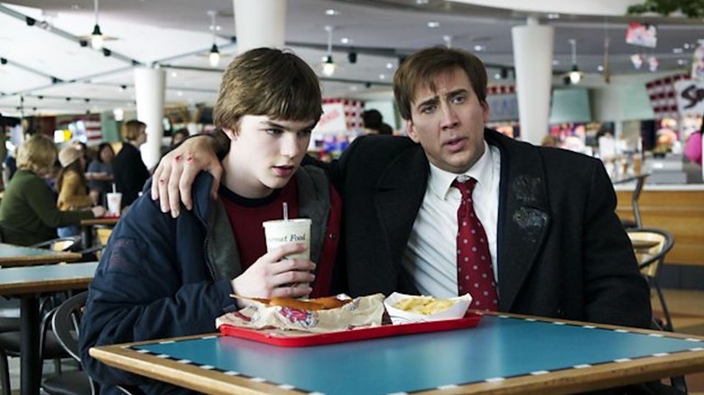 Nicolas Cage as David Spritz throws his arm around Nicholas Hoult as Mike Spritzel in a food court in The Weather Man