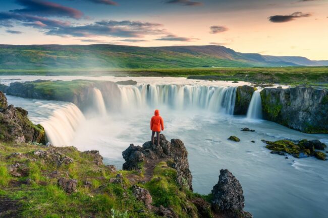 0_Godafoss-waterfall-flowing-with-colorful-sunset-sky-and-male-tourist-standing-on-cliff-in-summer-at-Iceland.jpg