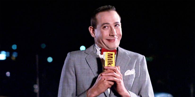 Paul Reubens holds a candy bar and smiles in Pee-wee's Big Adventure