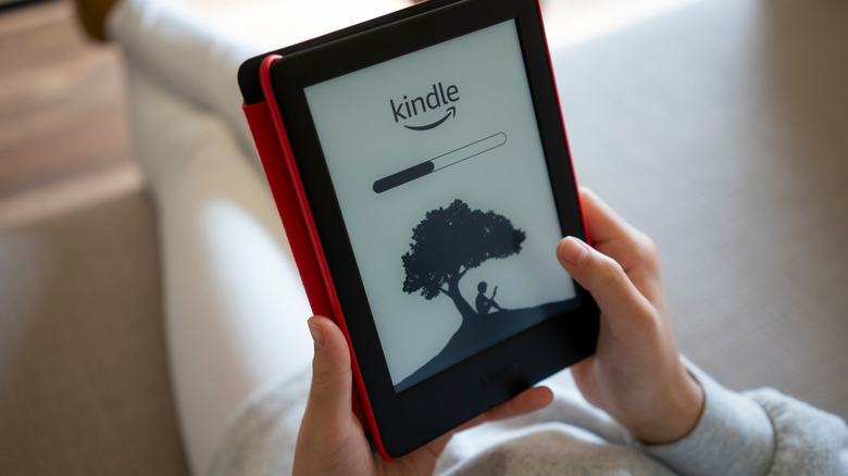 Person sitting on a couch holding a Kindle
