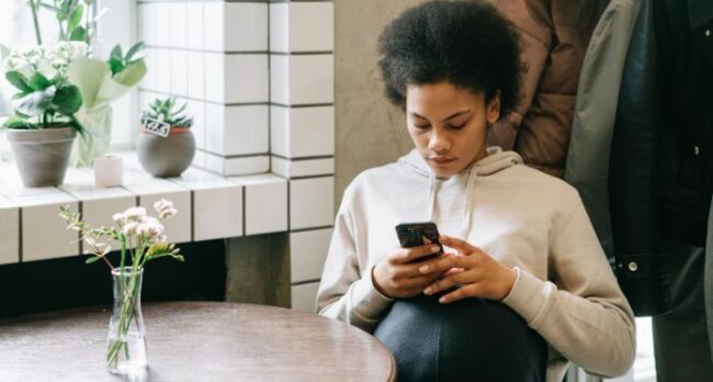 Image-of-a-Black-woman-reading-on-her-phone-at-a-table.jpg.optimal.jpg