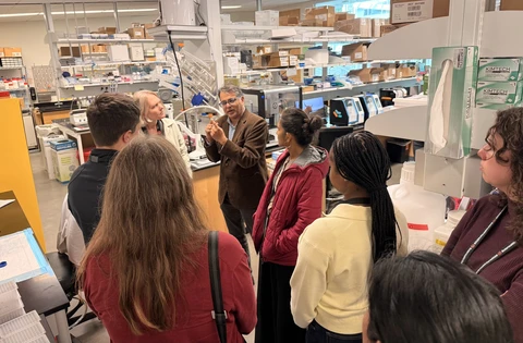 Conference attendees listening to a researcher during a field trip to a research lab.