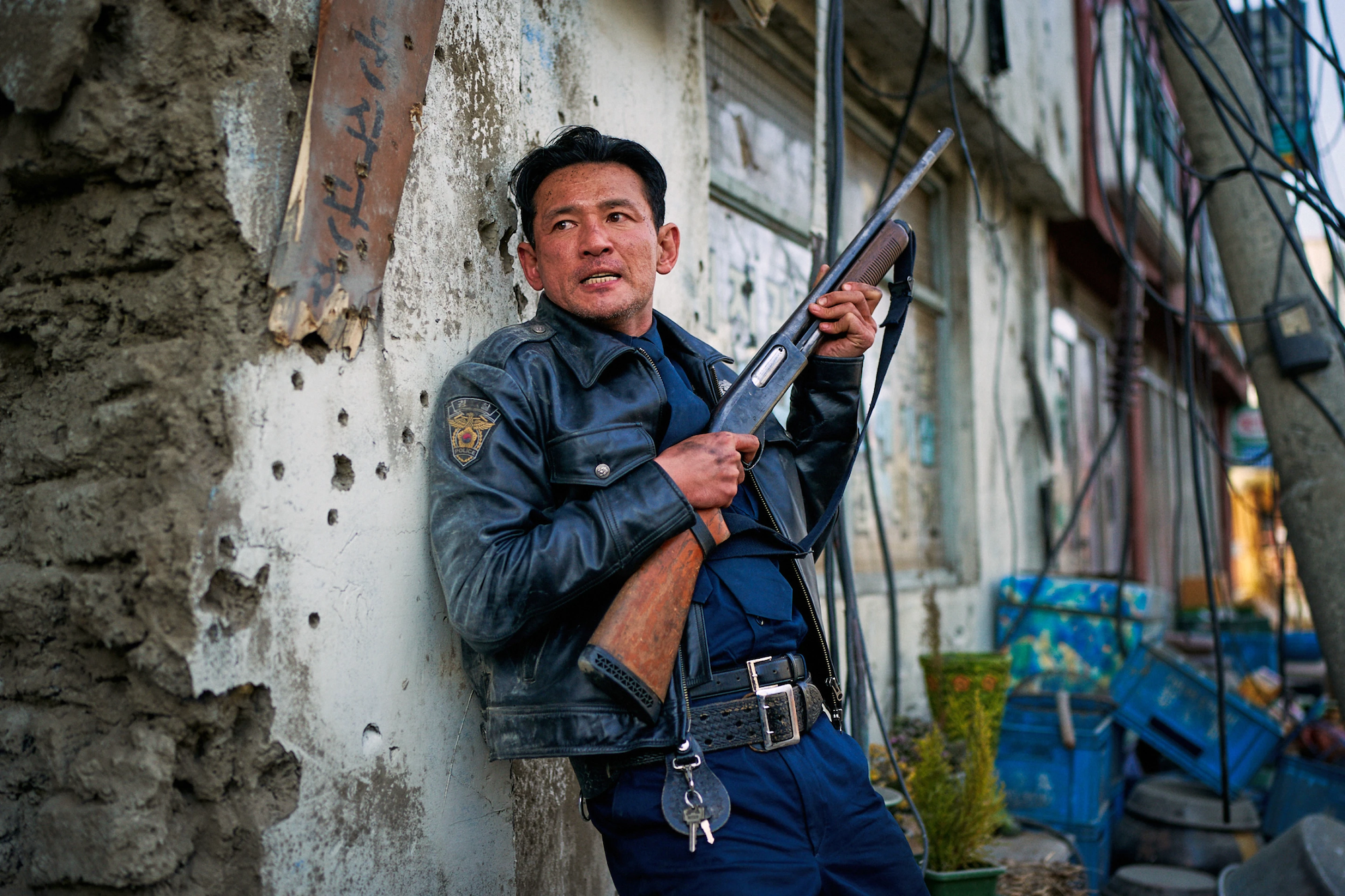 a Korean man in a police uniform holding a rifle