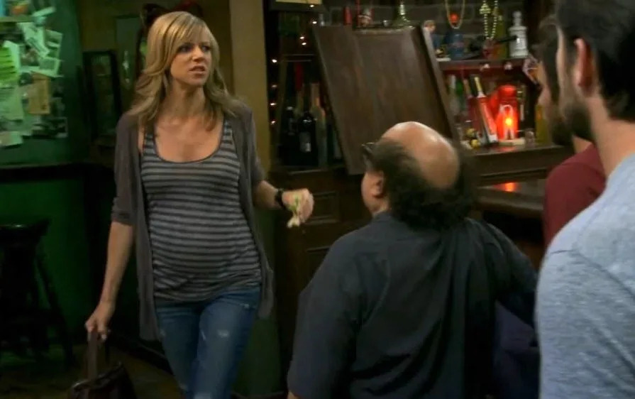 Scene from a TV show with Dee in casual wear confronting two men in a bar setting