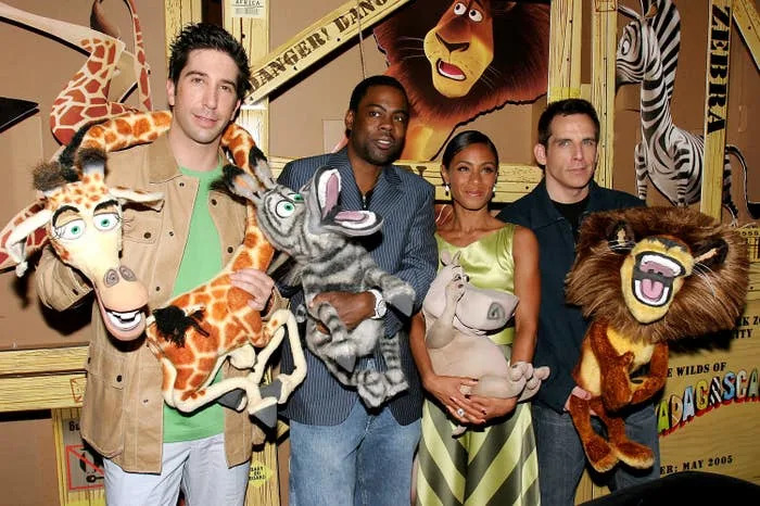 Four people hold plush character props from