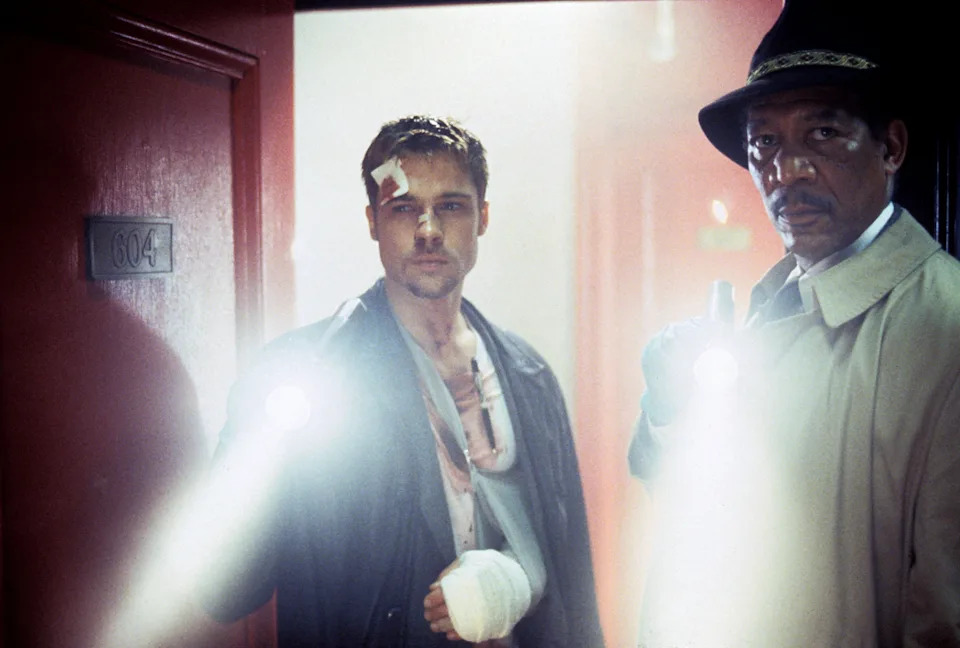 Two detectives, one with a bandaged hand, holding flashlights in a suspenseful scene from a movie