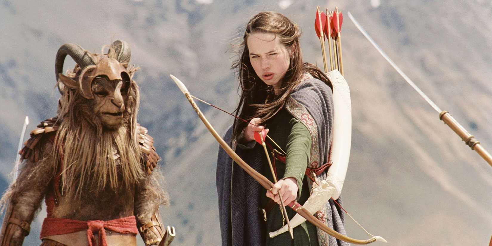 Anna Popplewell as Susan drawing a bow and arrow with a fantasy creature nearby in The Chronicles of Narnia: The Lion, the Witch and the Wardrobe.